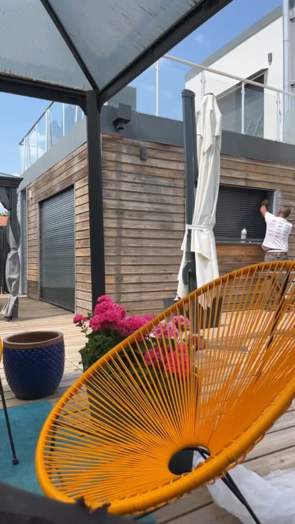 Artisan au travail sur la façade d'une maison contemporaine avec terrasse en bois, à Lyon