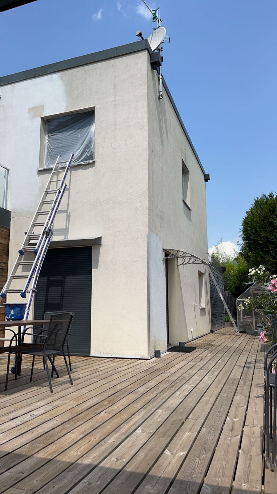 Façade crème d'une maison à toit plat, avec échelle et fenêtre protégée par un film, à Lyon