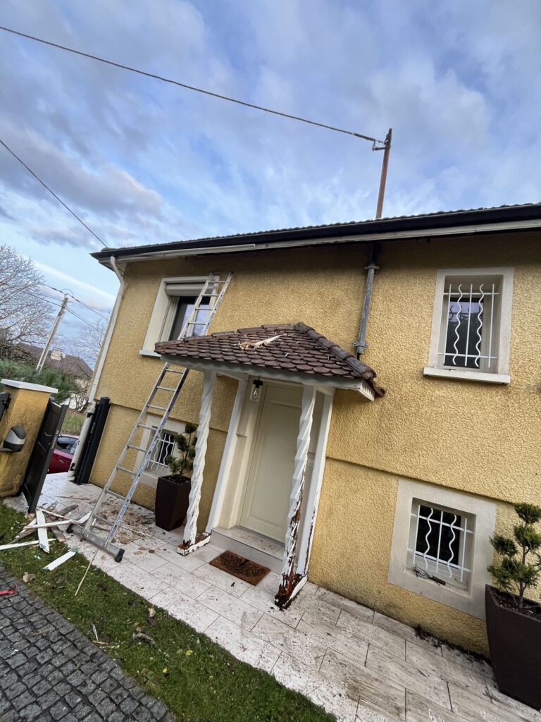 Auvent d'entrée avec débris et échelle devant une maison jaune, à Lyon