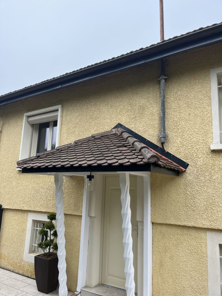 Gouttière avec ancienne descente en zinc au-dessus de l'auvent d'entrée, à Lyon