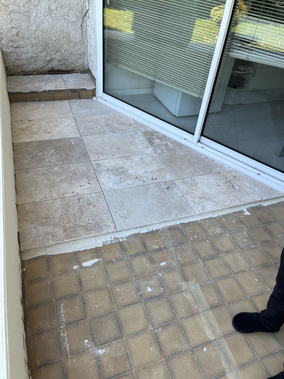 Terrasse partiellement recarrelée en carrelage clair à côté de l'ancien sol brun, à Lyon