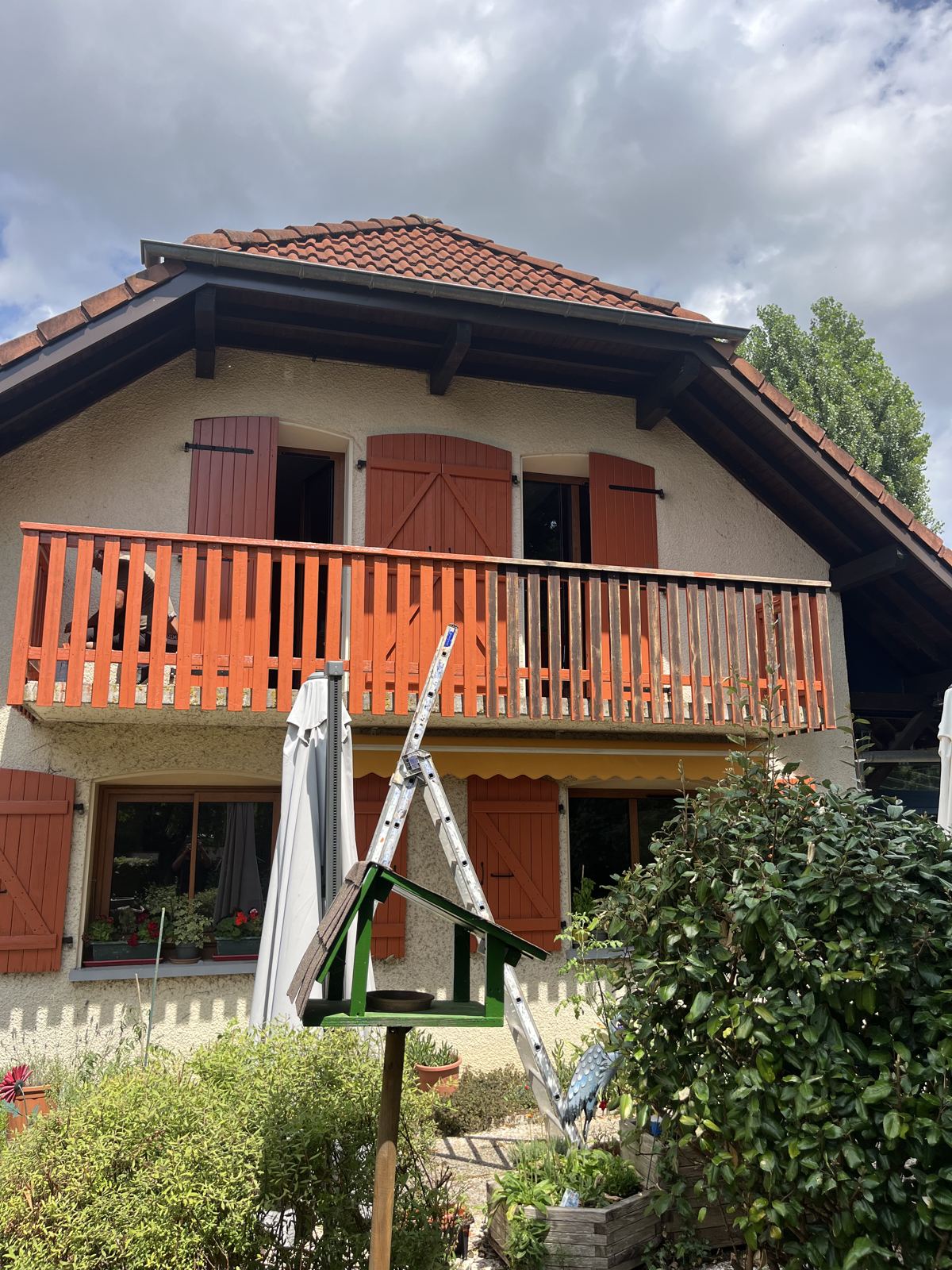 Balcon et volets repeints en orange sur une maison de style chalet, à Lyon